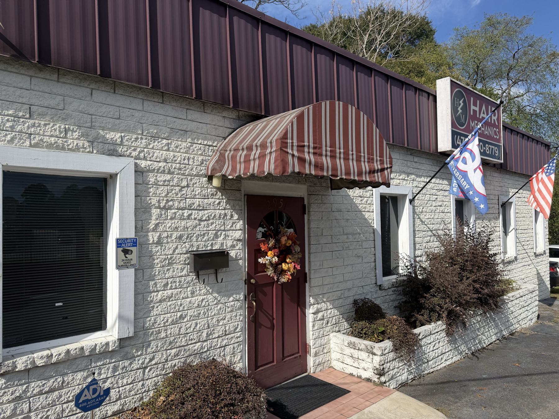 The Hair Mechanics storefront on Vineville Ave, with its maroon door and striped awning